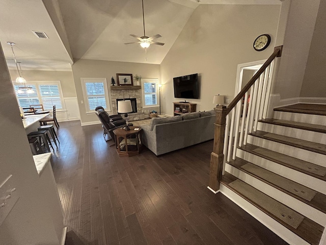 living room with dark wood-type flooring, ceiling fan, a fireplace, and high vaulted ceiling