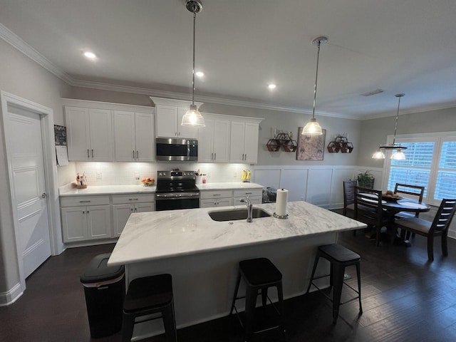 kitchen featuring white cabinetry, appliances with stainless steel finishes, a breakfast bar area, and decorative light fixtures