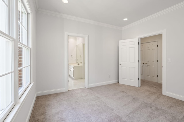 unfurnished bedroom with multiple windows, ornamental molding, light colored carpet, and ensuite bathroom