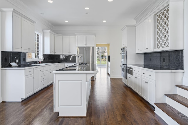 kitchen with appliances with stainless steel finishes, white cabinetry, sink, a kitchen island with sink, and dark wood-type flooring