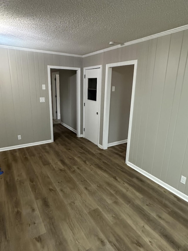 spare room featuring dark hardwood / wood-style flooring, crown molding, and a textured ceiling