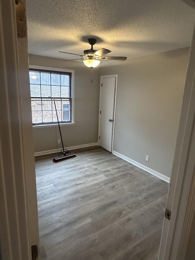 empty room with hardwood / wood-style floors, a textured ceiling, and ceiling fan