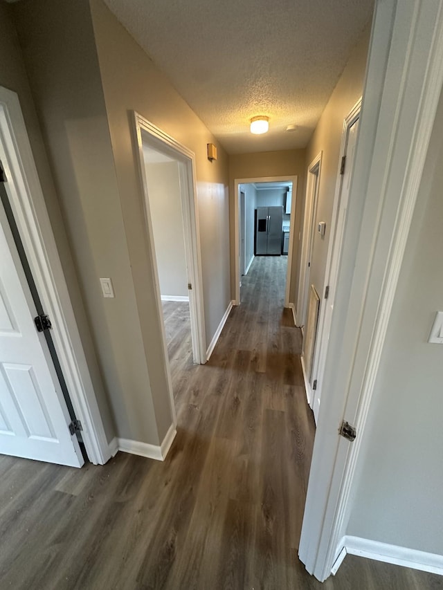 corridor with dark hardwood / wood-style flooring and a textured ceiling