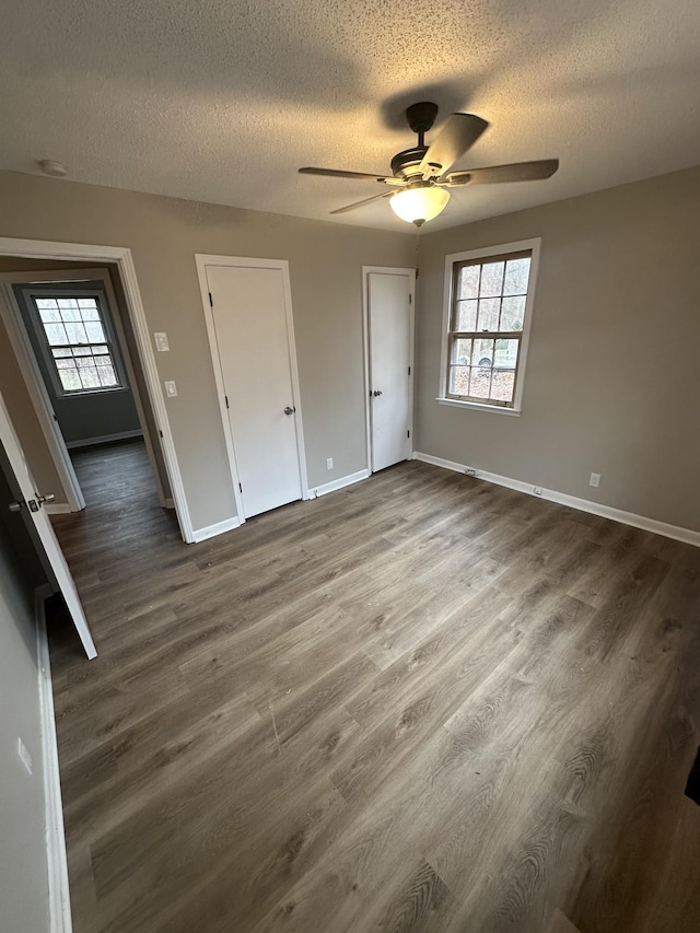 unfurnished bedroom with dark wood-type flooring, multiple windows, and a textured ceiling