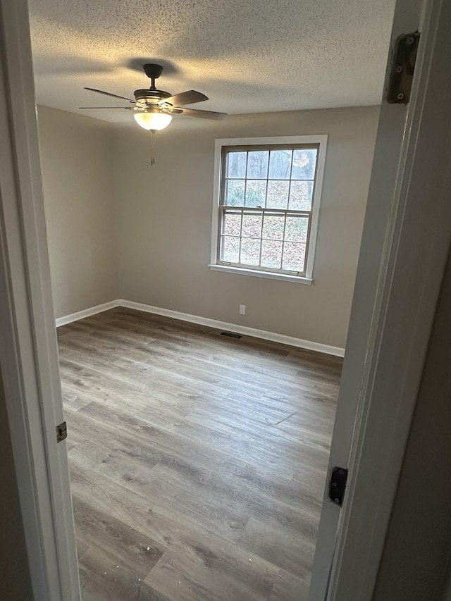 unfurnished room featuring ceiling fan, hardwood / wood-style floors, and a textured ceiling