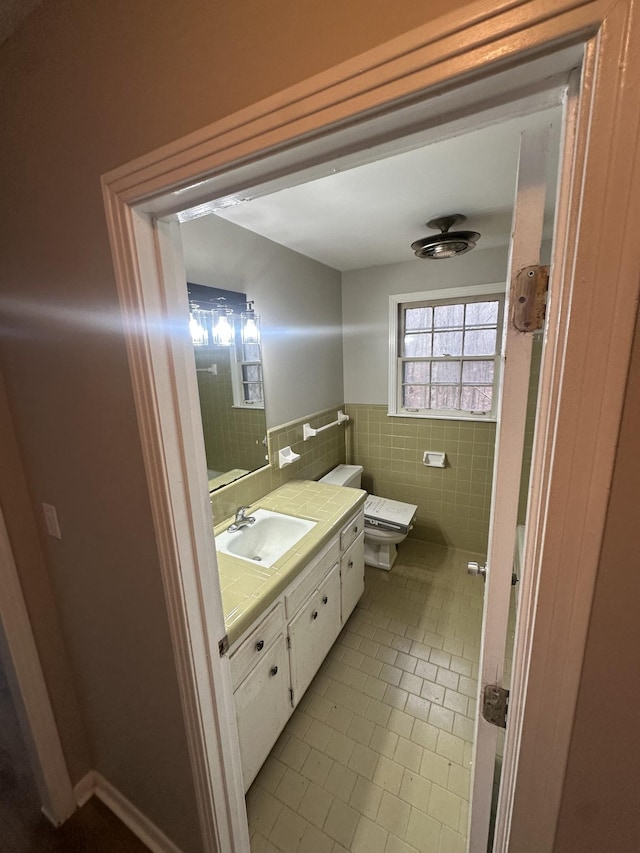 bathroom with tile patterned flooring, vanity, toilet, and tile walls