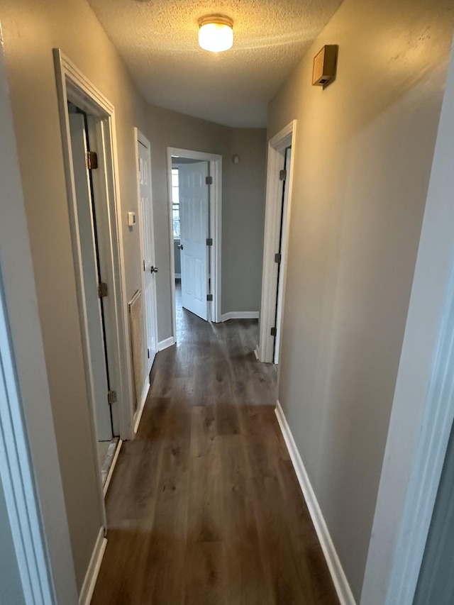 hall with dark hardwood / wood-style flooring and a textured ceiling