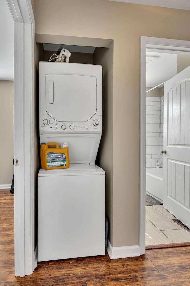 laundry area with stacked washing maching and dryer and dark wood-type flooring