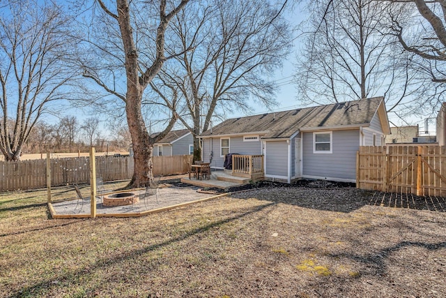 back of property with a yard, a deck, and a fire pit