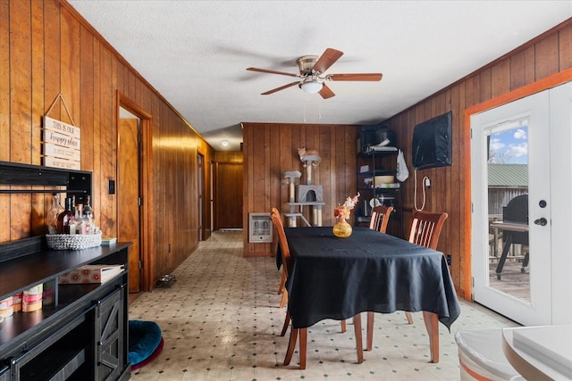 dining room with crown molding, ceiling fan, heating unit, a textured ceiling, and wood walls