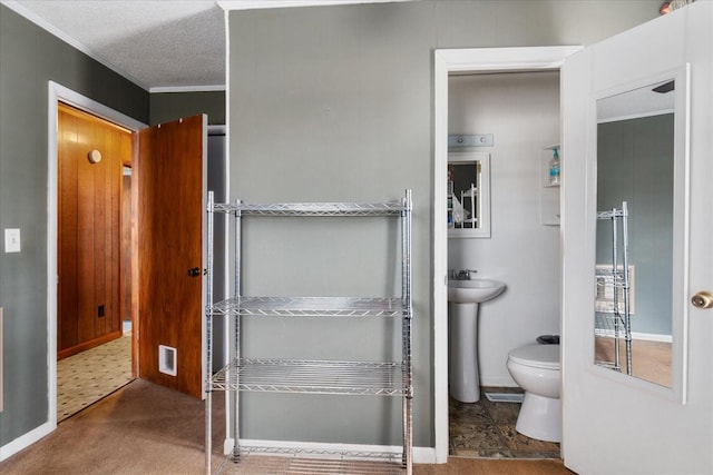 bathroom with ornamental molding, toilet, sink, and a textured ceiling