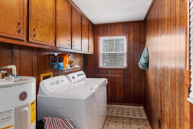 clothes washing area featuring independent washer and dryer, cabinets, wooden walls, and water heater