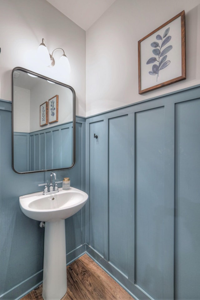 bathroom featuring a wainscoted wall, a decorative wall, and wood finished floors