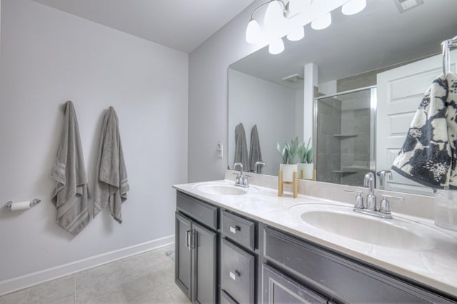 bathroom featuring double vanity, a shower stall, baseboards, and a sink