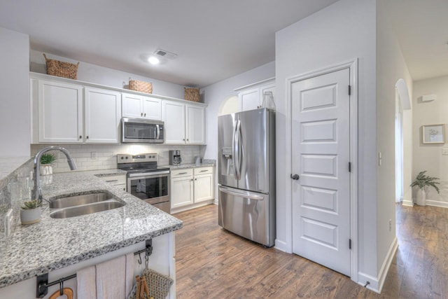 kitchen featuring sink, stainless steel appliances, light stone counters, tasteful backsplash, and white cabinets