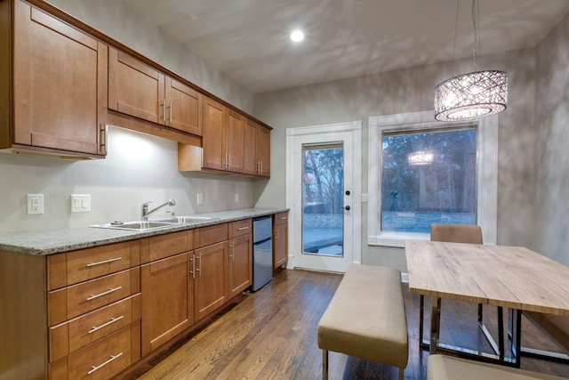 kitchen featuring hanging light fixtures, light stone countertops, sink, and dark wood-type flooring