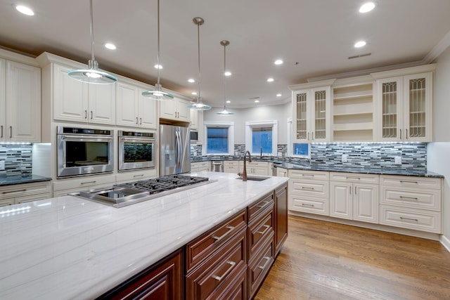 kitchen featuring stainless steel appliances, pendant lighting, white cabinets, and dark stone counters