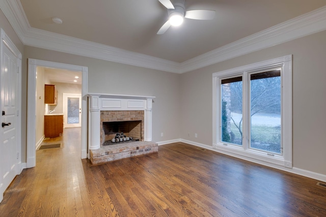 unfurnished living room featuring hardwood / wood-style flooring, ceiling fan, ornamental molding, and a brick fireplace