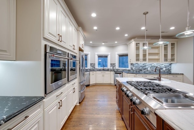 kitchen featuring dark stone countertops, stainless steel appliances, decorative light fixtures, and white cabinets