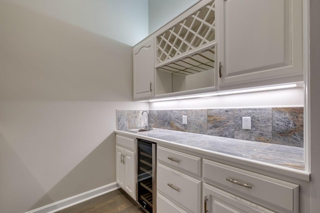 kitchen featuring sink, white cabinetry, dark hardwood / wood-style floors, beverage cooler, and decorative backsplash