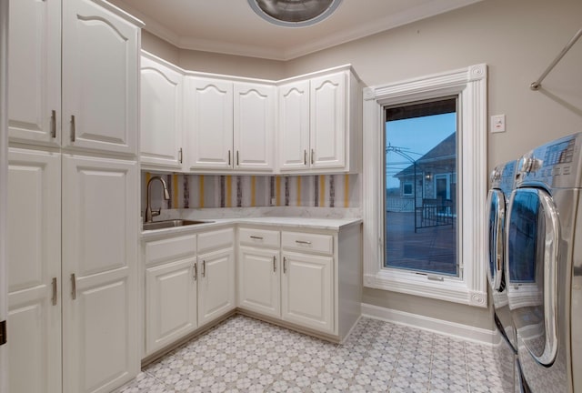 laundry room featuring cabinets, ornamental molding, washer and clothes dryer, and sink