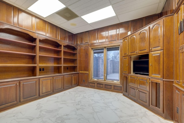 unfurnished office featuring a drop ceiling and wooden walls