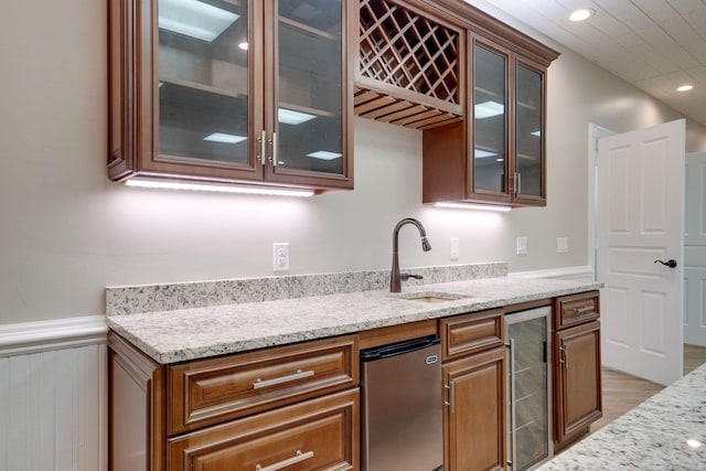 kitchen featuring wine cooler, sink, light stone counters, and light hardwood / wood-style flooring