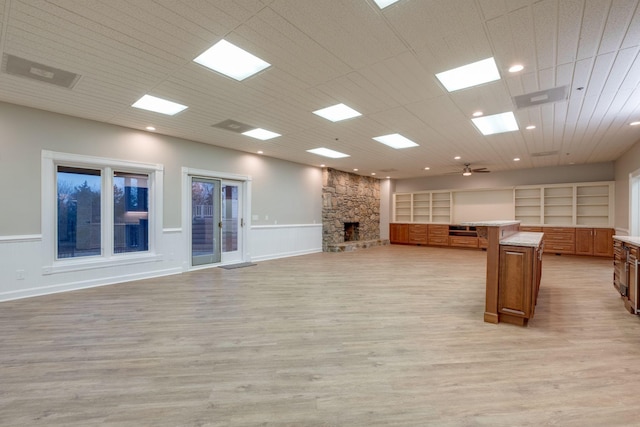 unfurnished living room with ceiling fan, a fireplace, and light hardwood / wood-style flooring