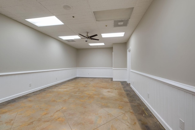 unfurnished room with ceiling fan, a paneled ceiling, and concrete flooring