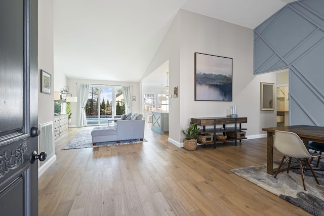 living room with high vaulted ceiling and light wood-type flooring