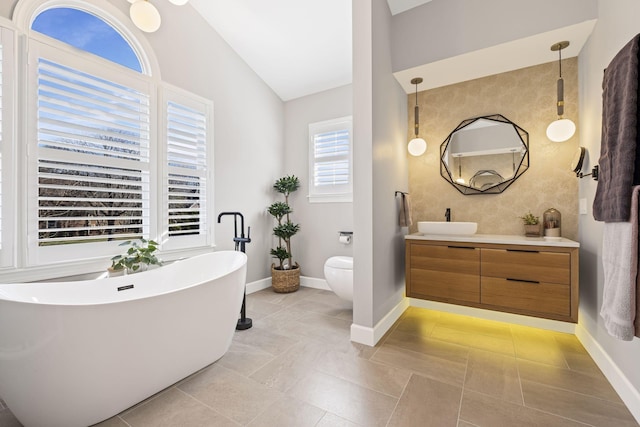 bathroom with lofted ceiling, a tub to relax in, toilet, and vanity