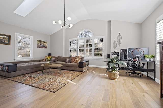 living room featuring a notable chandelier, a skylight, high vaulted ceiling, and light wood-type flooring