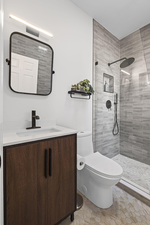 bathroom with vanity, a tile shower, tile patterned floors, and toilet