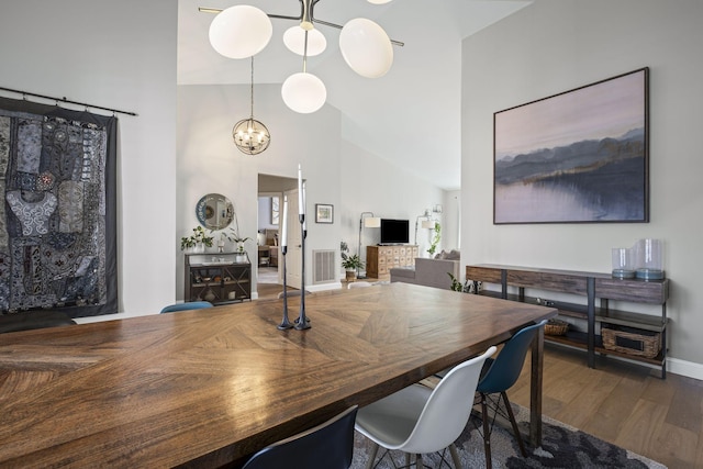 dining room featuring dark hardwood / wood-style flooring, a chandelier, and high vaulted ceiling