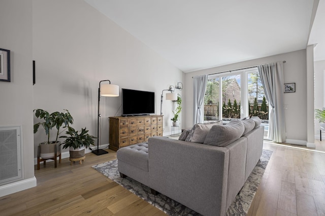 living room with hardwood / wood-style floors and high vaulted ceiling