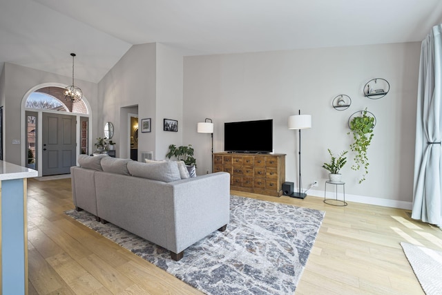 living room featuring an inviting chandelier, light hardwood / wood-style flooring, and high vaulted ceiling