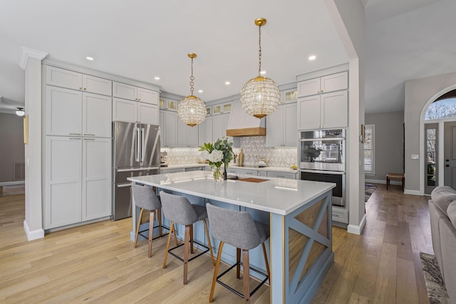 kitchen with a breakfast bar, tasteful backsplash, decorative light fixtures, a center island with sink, and stainless steel appliances