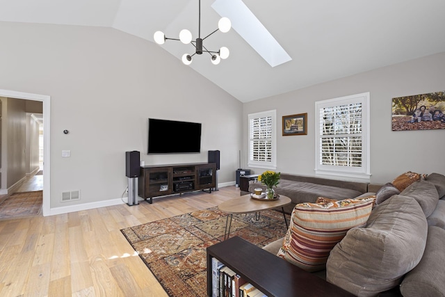 living room with an inviting chandelier, hardwood / wood-style floors, a skylight, and high vaulted ceiling