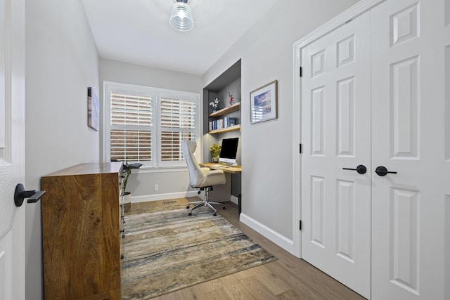 home office featuring built in shelves and light wood-type flooring