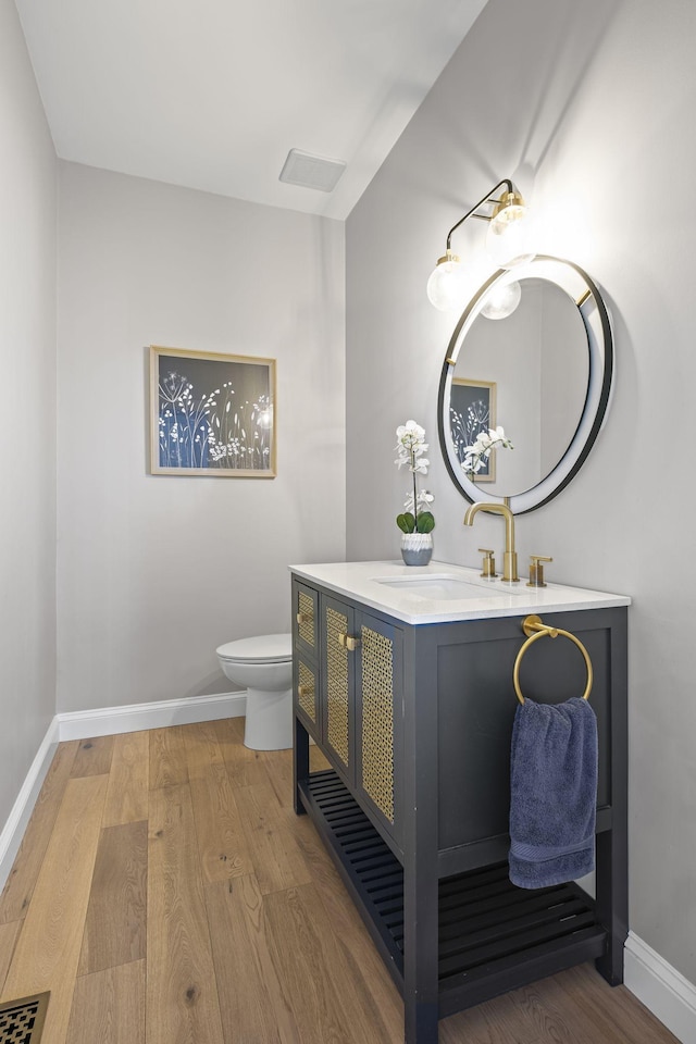 bathroom featuring wood-type flooring, vanity, and toilet