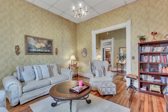 living room featuring a drop ceiling, hardwood / wood-style flooring, and a chandelier