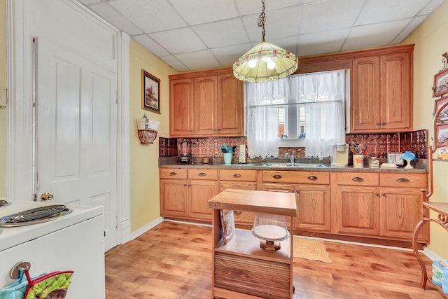 kitchen featuring sink, light hardwood / wood-style flooring, a paneled ceiling, tasteful backsplash, and decorative light fixtures