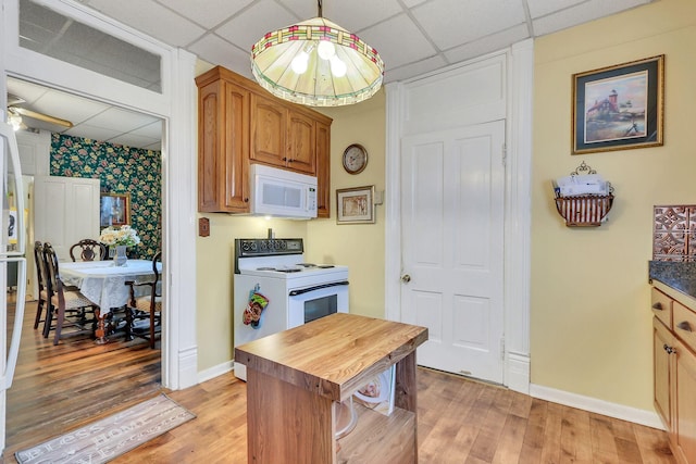 kitchen with pendant lighting, white appliances, light hardwood / wood-style flooring, and a drop ceiling