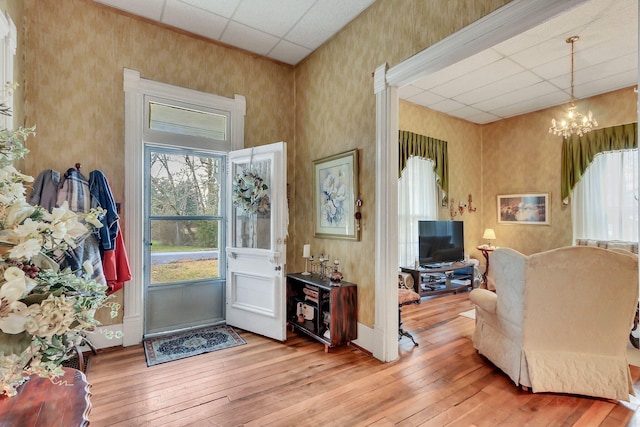 entrance foyer featuring a drop ceiling, wood-type flooring, and an inviting chandelier