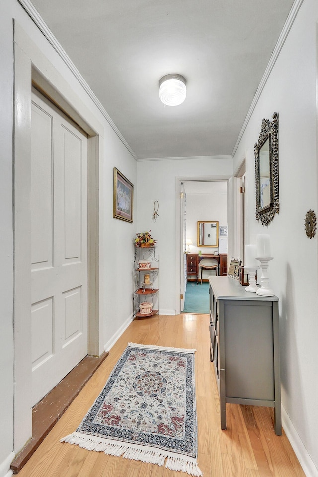 hallway featuring crown molding and light hardwood / wood-style flooring