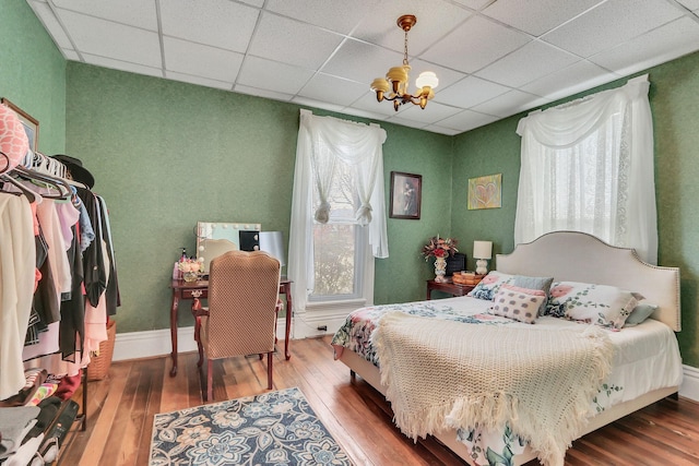 bedroom featuring hardwood / wood-style flooring, a paneled ceiling, and a notable chandelier