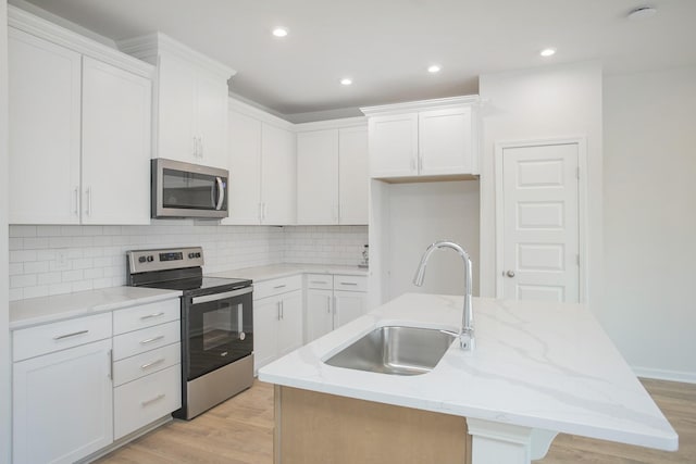 kitchen featuring white cabinetry, stainless steel appliances, and a center island with sink