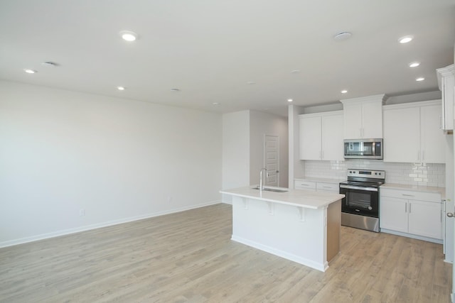 kitchen with white cabinetry, appliances with stainless steel finishes, a kitchen island with sink, and sink