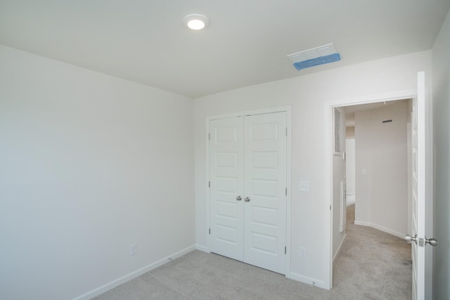 unfurnished bedroom featuring light colored carpet and a closet