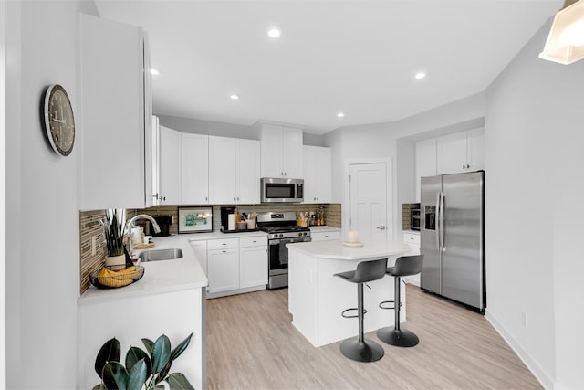 kitchen with sink, stainless steel appliances, a center island, white cabinets, and decorative backsplash